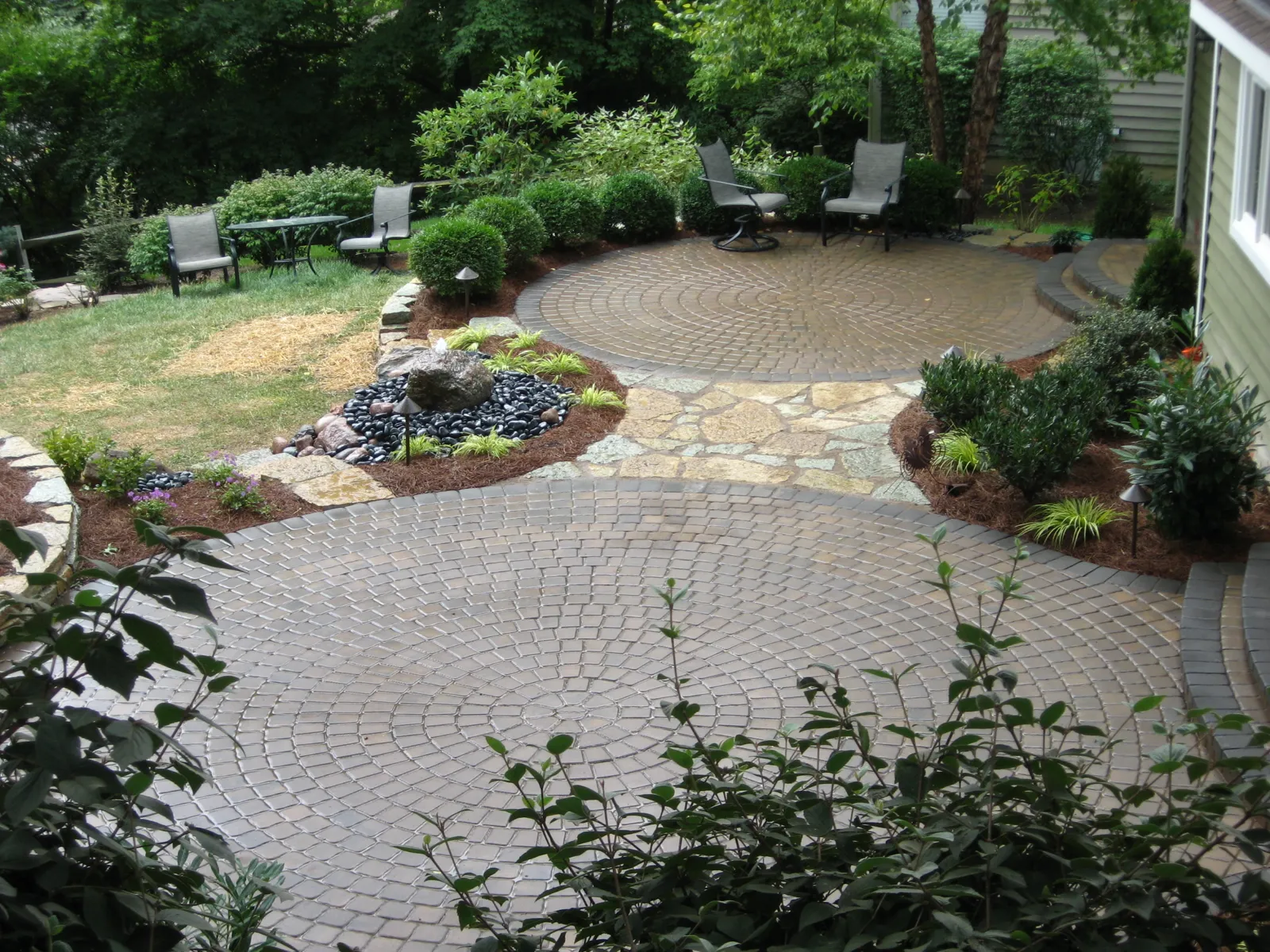 Flagstone walk and river rock feature connecting two paver patios