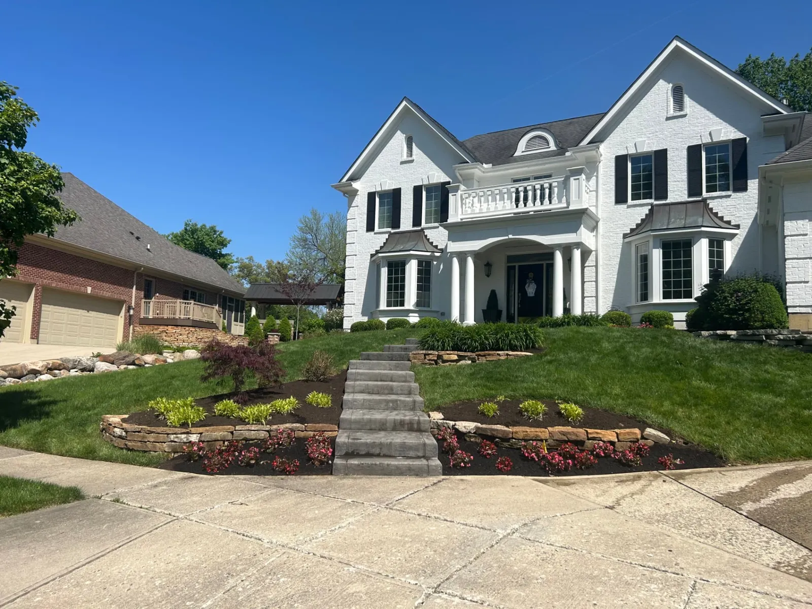 Tiered stone walls and center steps climbing a front lawn