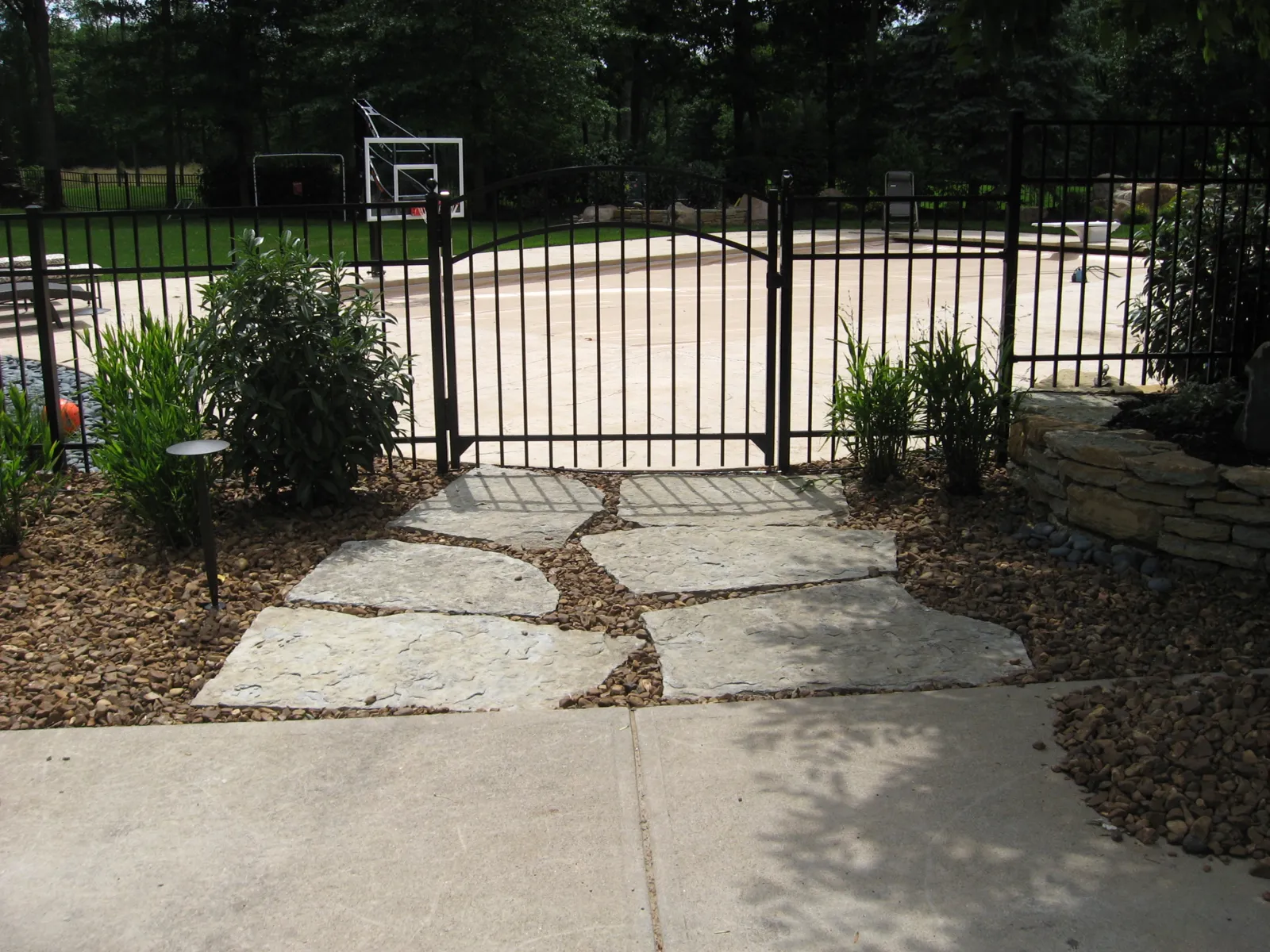 Limestone steppers leading to a black aluminum pool gate