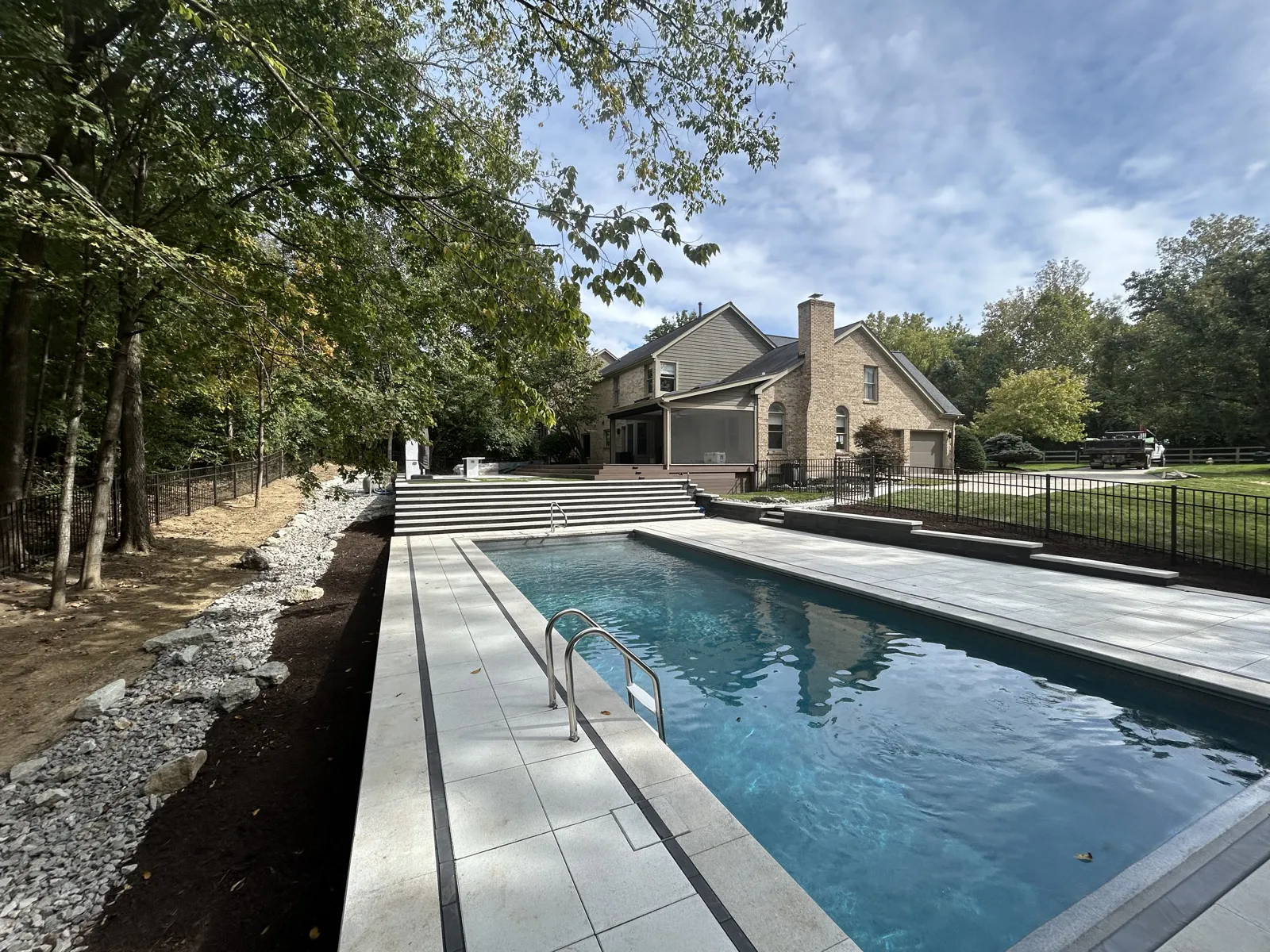 Long rectangular pool framed by a light paver deck and stone drainage edge