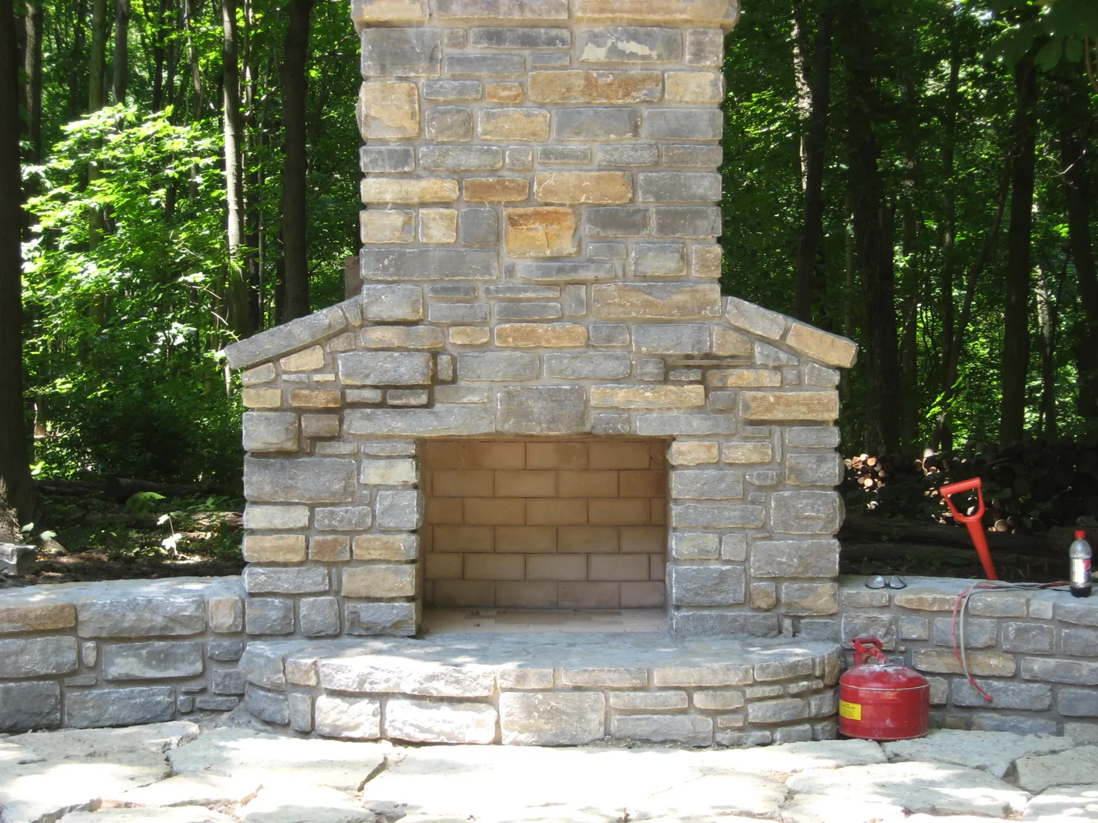 Custom natural stone wood-burning fireplace with seat wall hearth