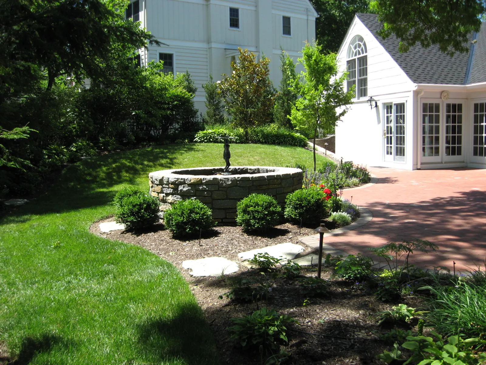 Stone fountain bed and brick walk in a manicured courtyard garden