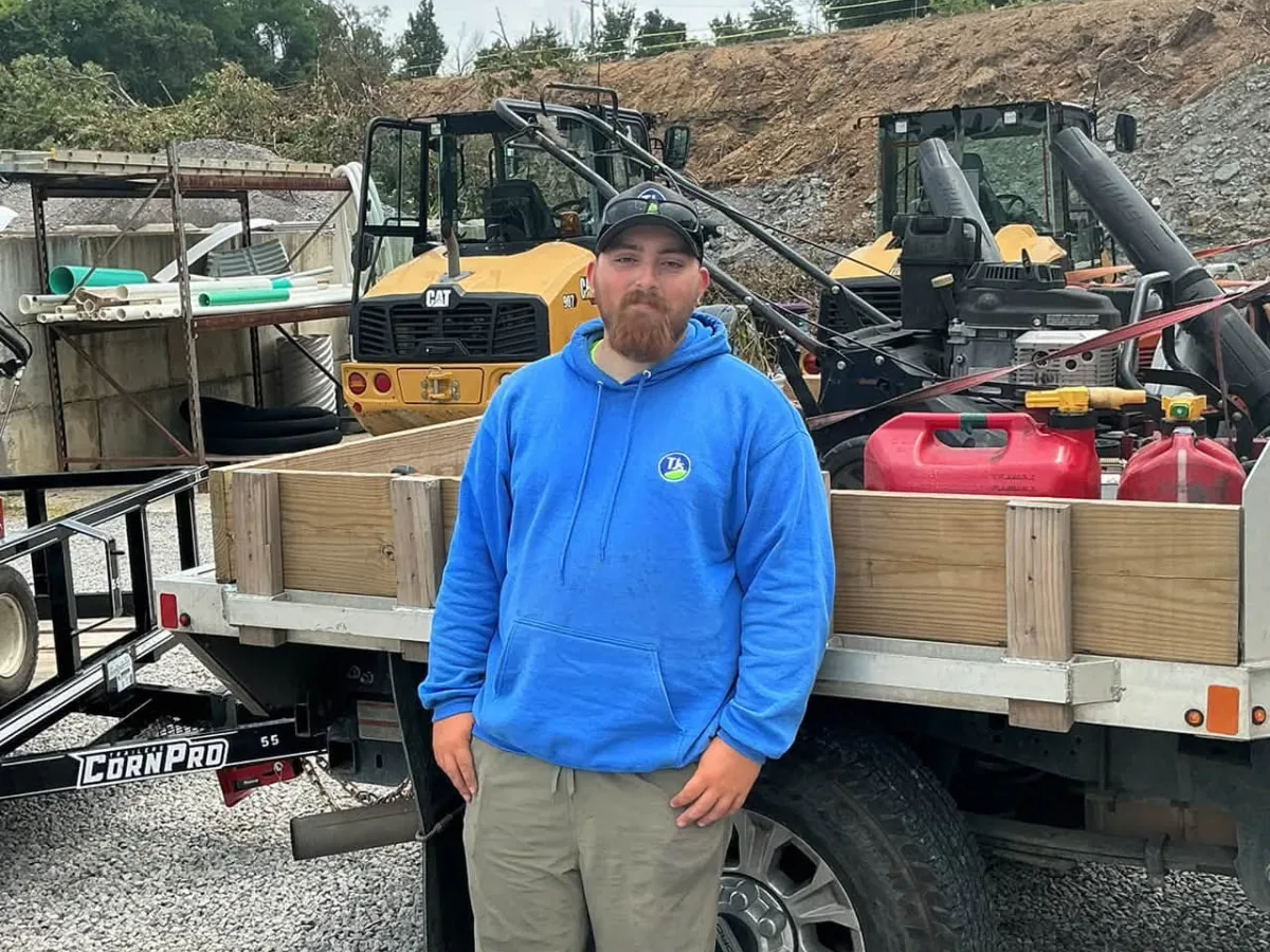 Property Maintenance Crew Leader Nick standing beside a TJs equipment truck