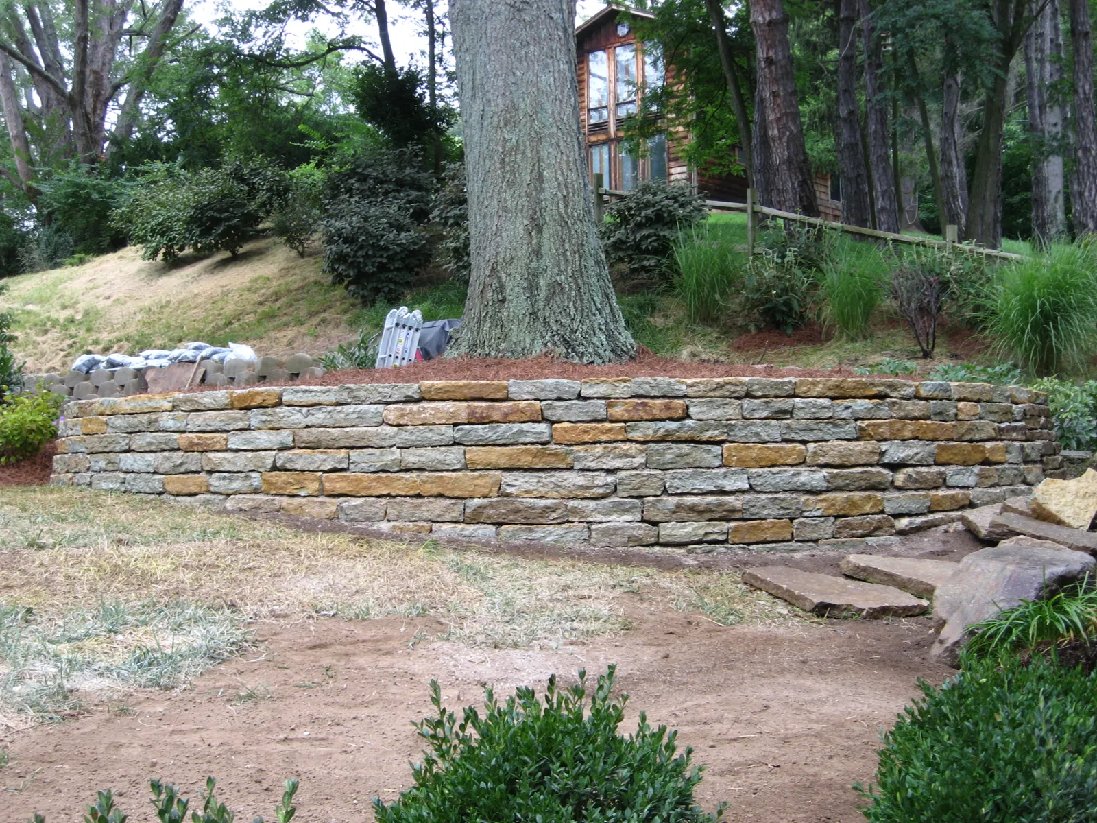 Long natural stone retaining wall holding back a sloped yard