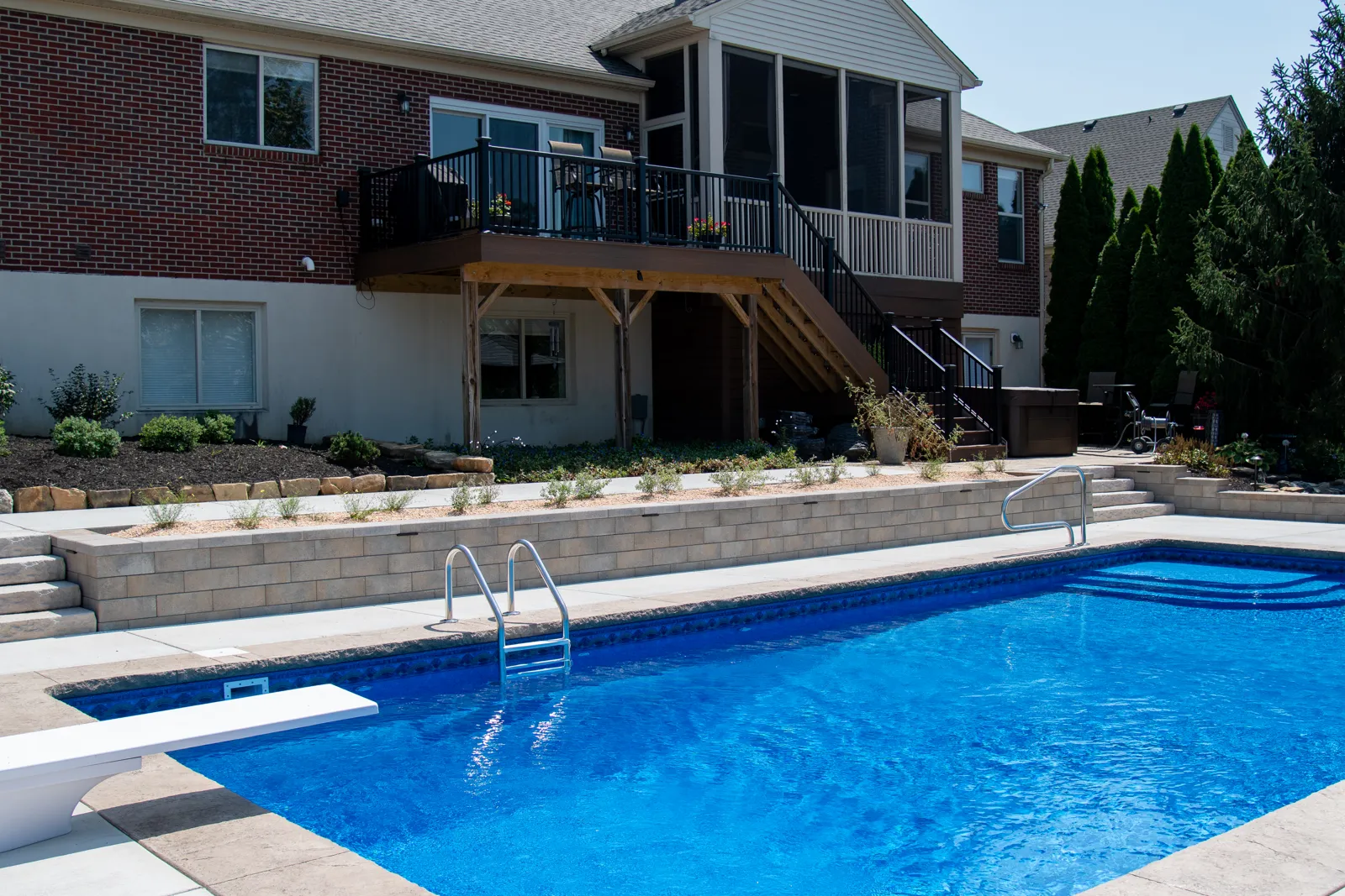 Layered planting beds above the retaining wall framing the pool