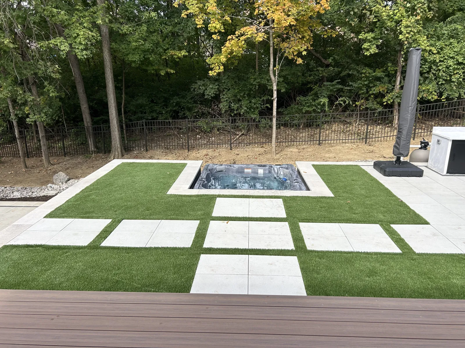 Sunken hot tub framed by custom artificial turf and paver inlays
