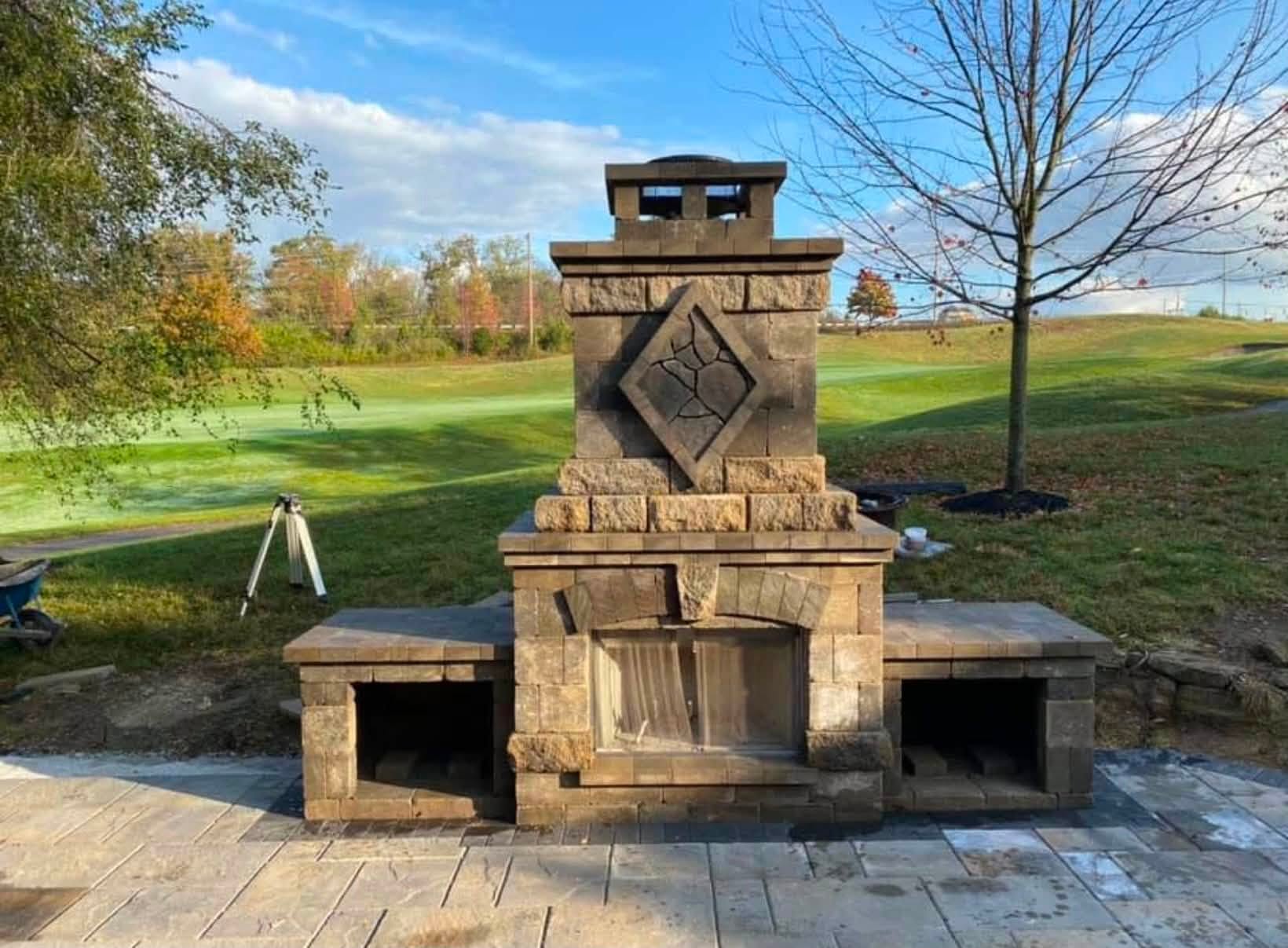 Paver block outdoor fireplace with diamond stone inlay and wood storage on a paver patio