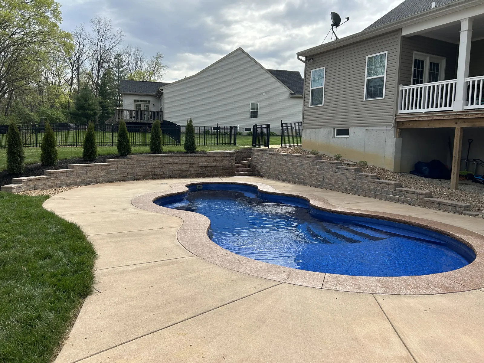 Freeform pool with concrete deck and block retaining wall