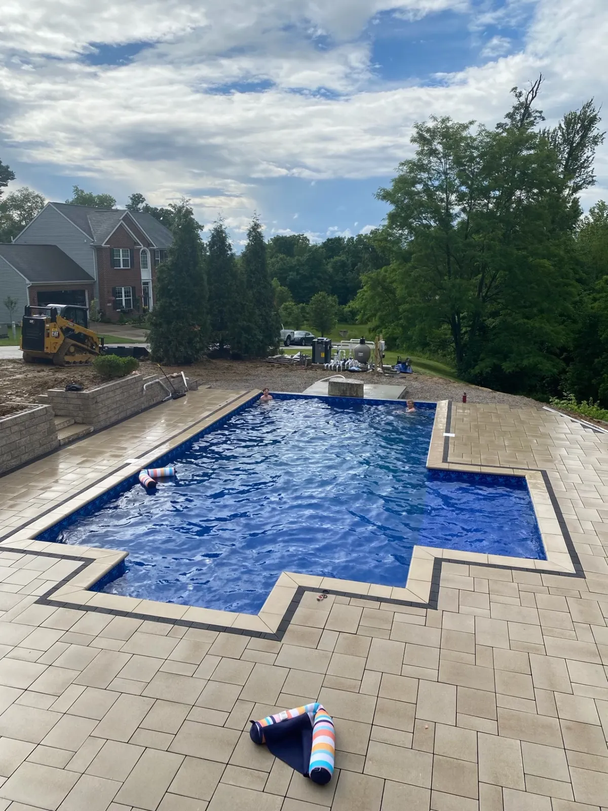 Completed pool and broad paver deck with retaining walls and landscaping