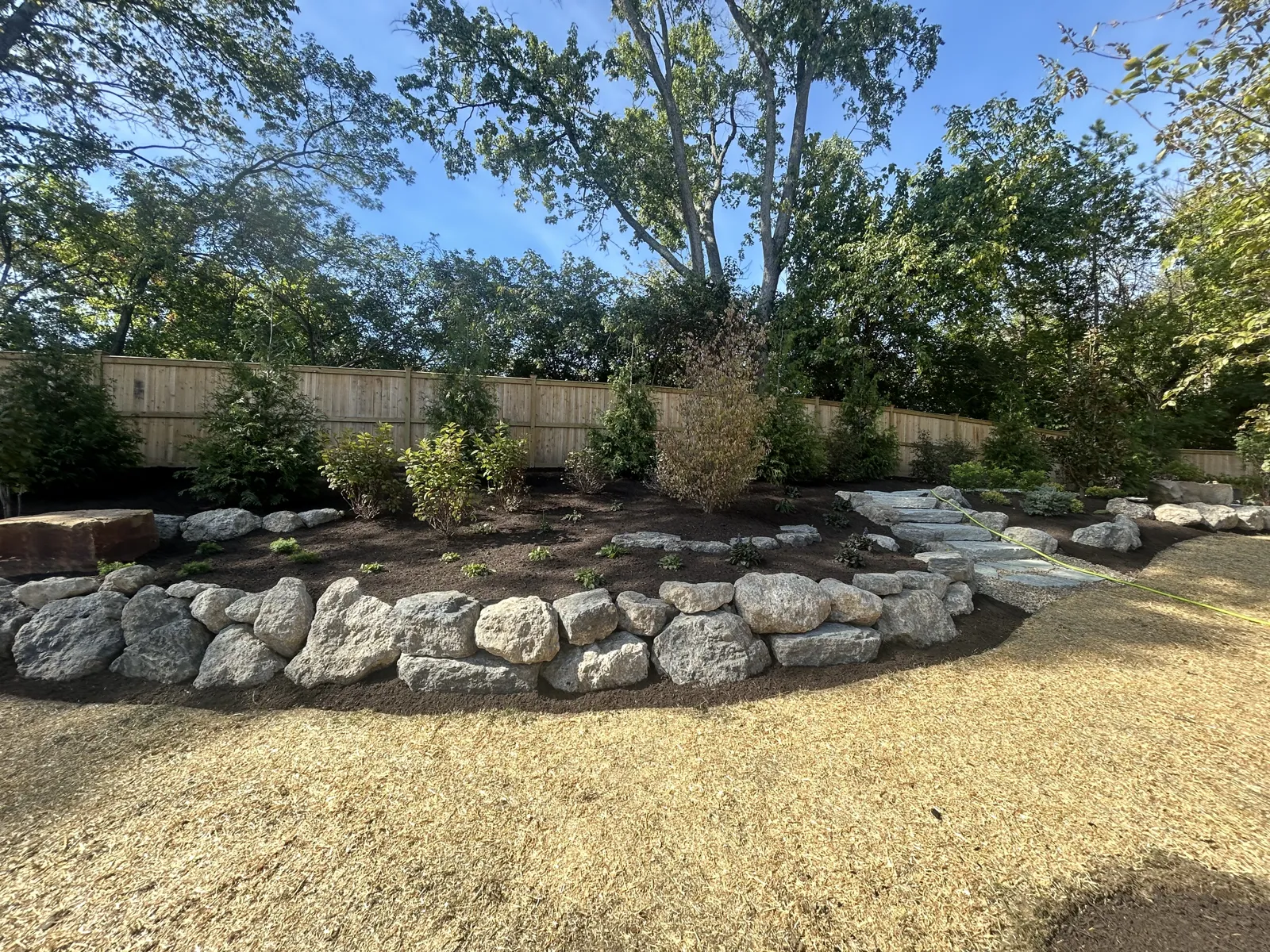 Natural boulder wall with stone steps and new plantings