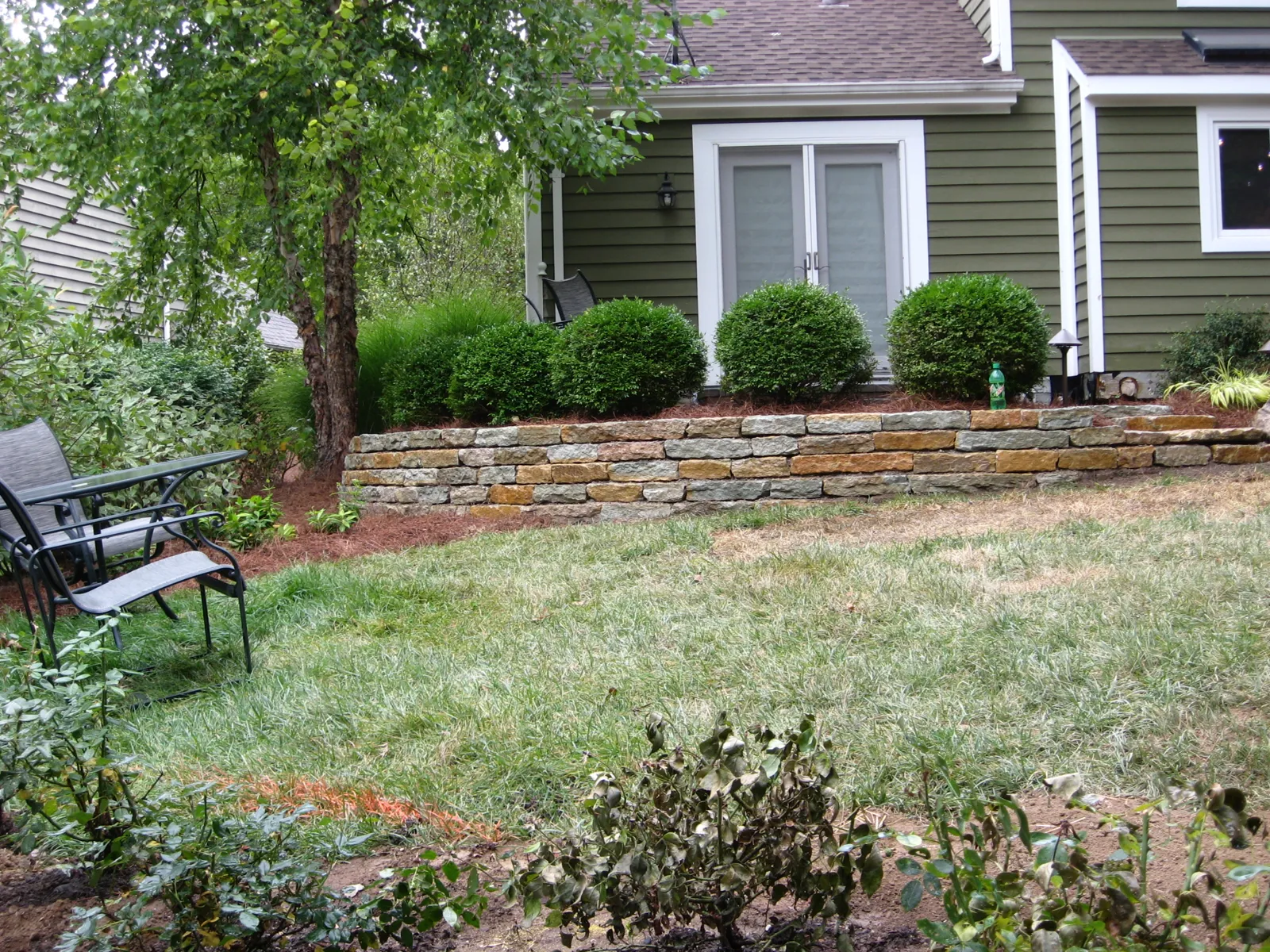 Natural stone wall and new lawn creating a level backyard