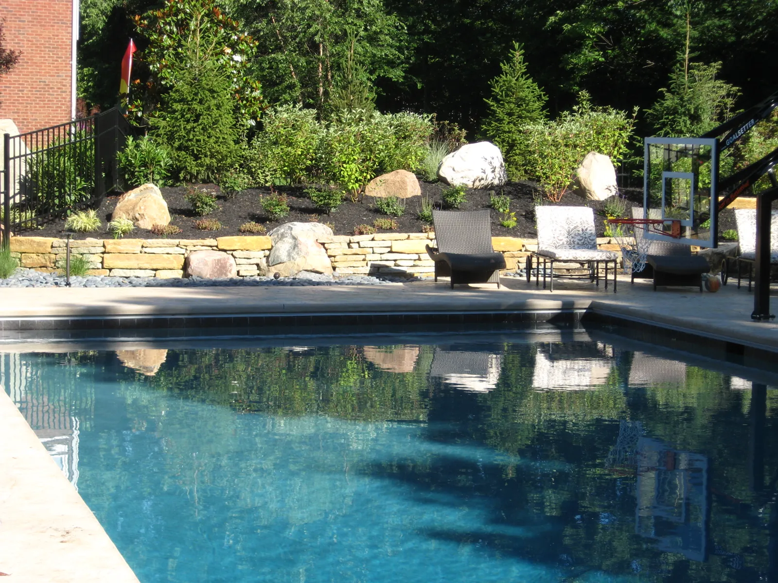 Pool bordered by a natural stone retaining wall and boulders