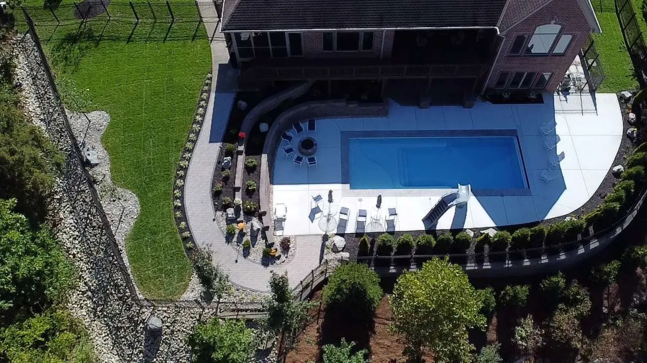 Aerial view of a geometric pool, paver terrace and stone walls