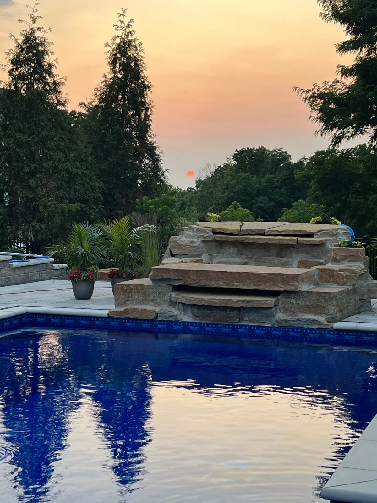 Close-up of a natural stone pool waterfall at sunset