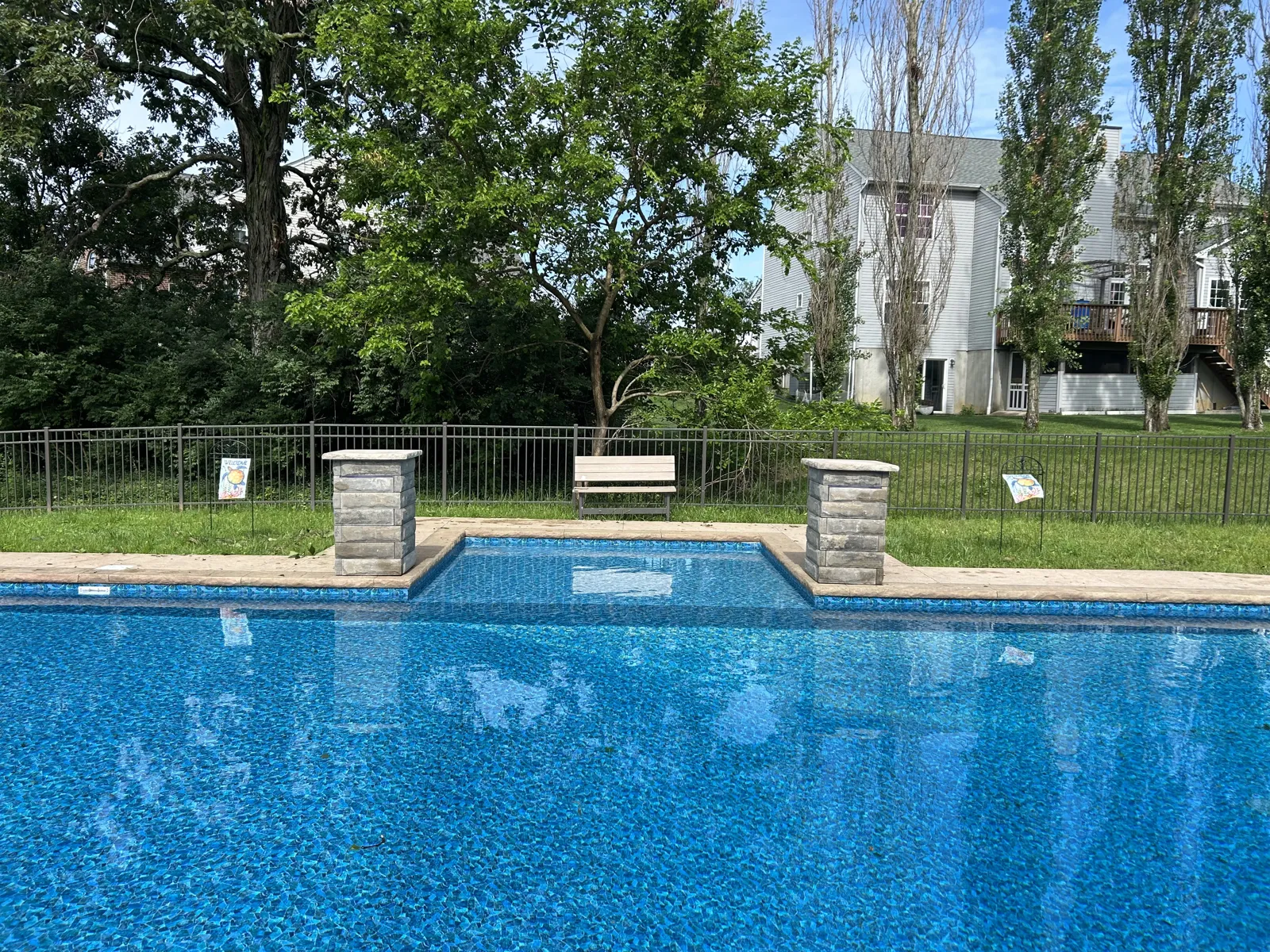 Pool edge with stone pillar accents and black fence