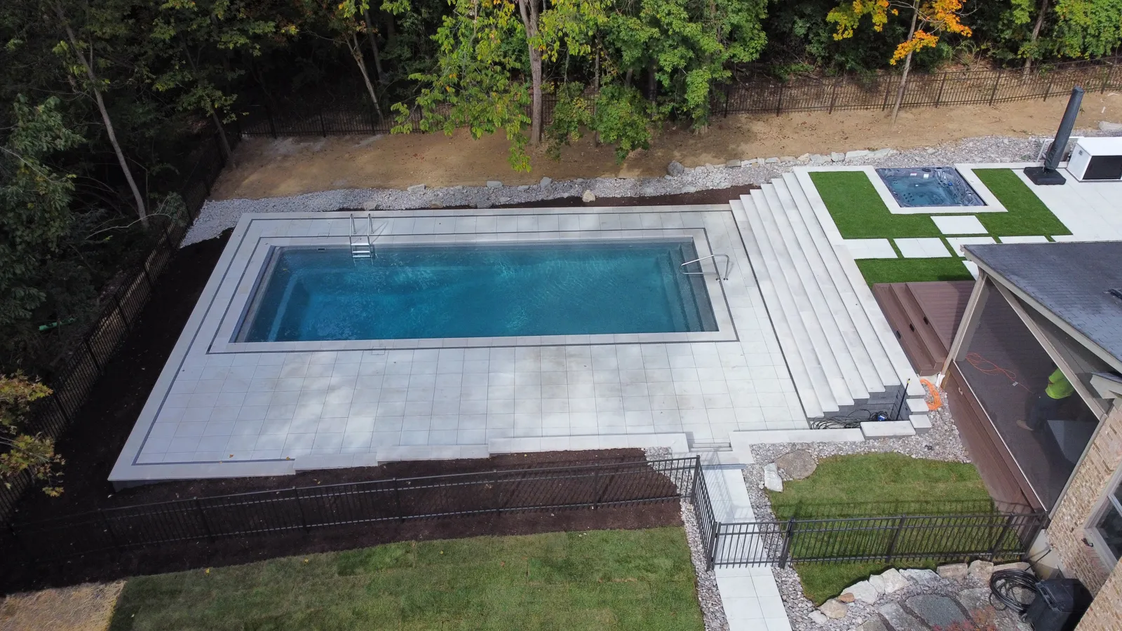 Drone view of wide stone stadium steps leading down to a rectangular pool deck