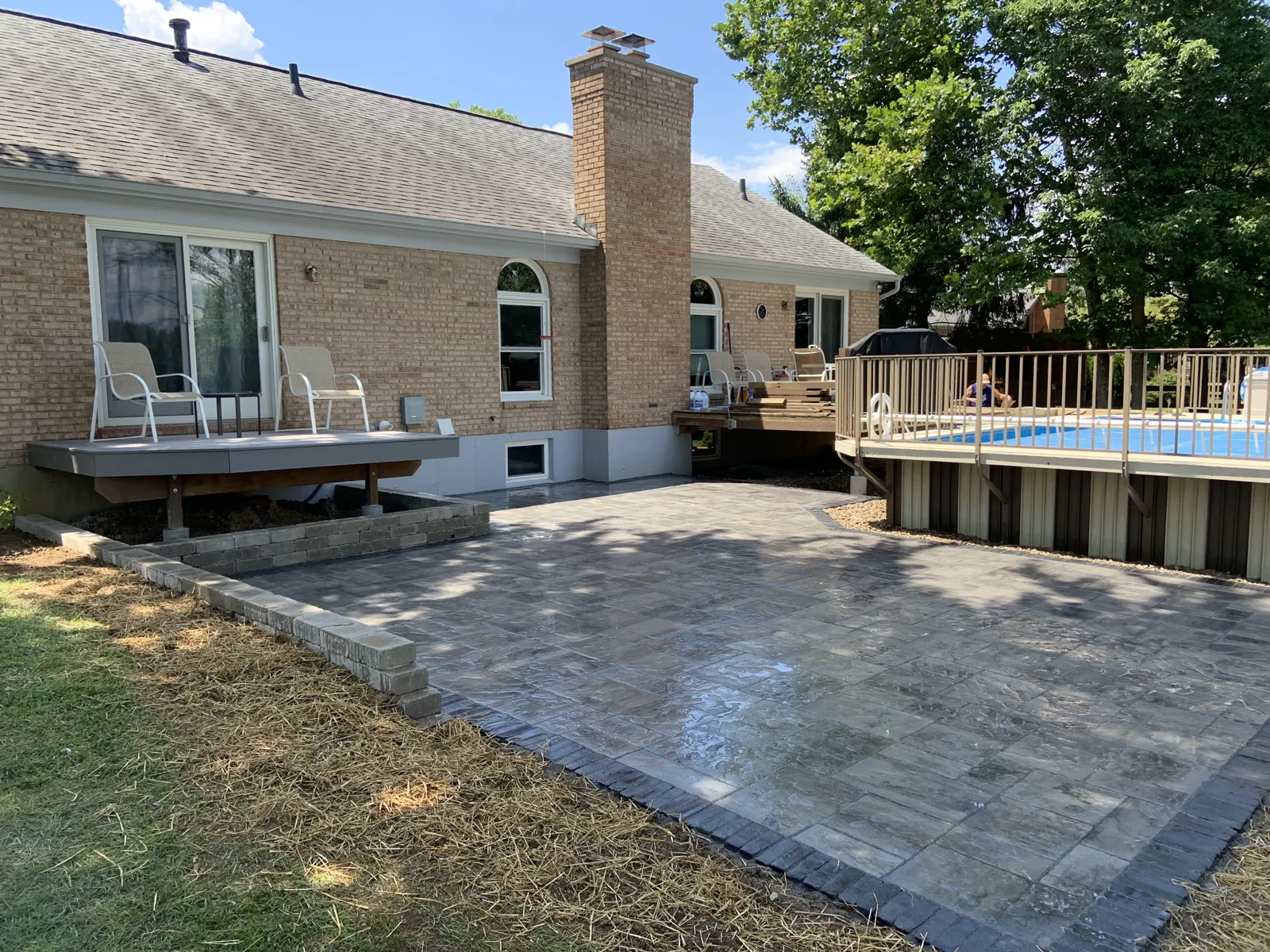 Large paver patio beside a deck