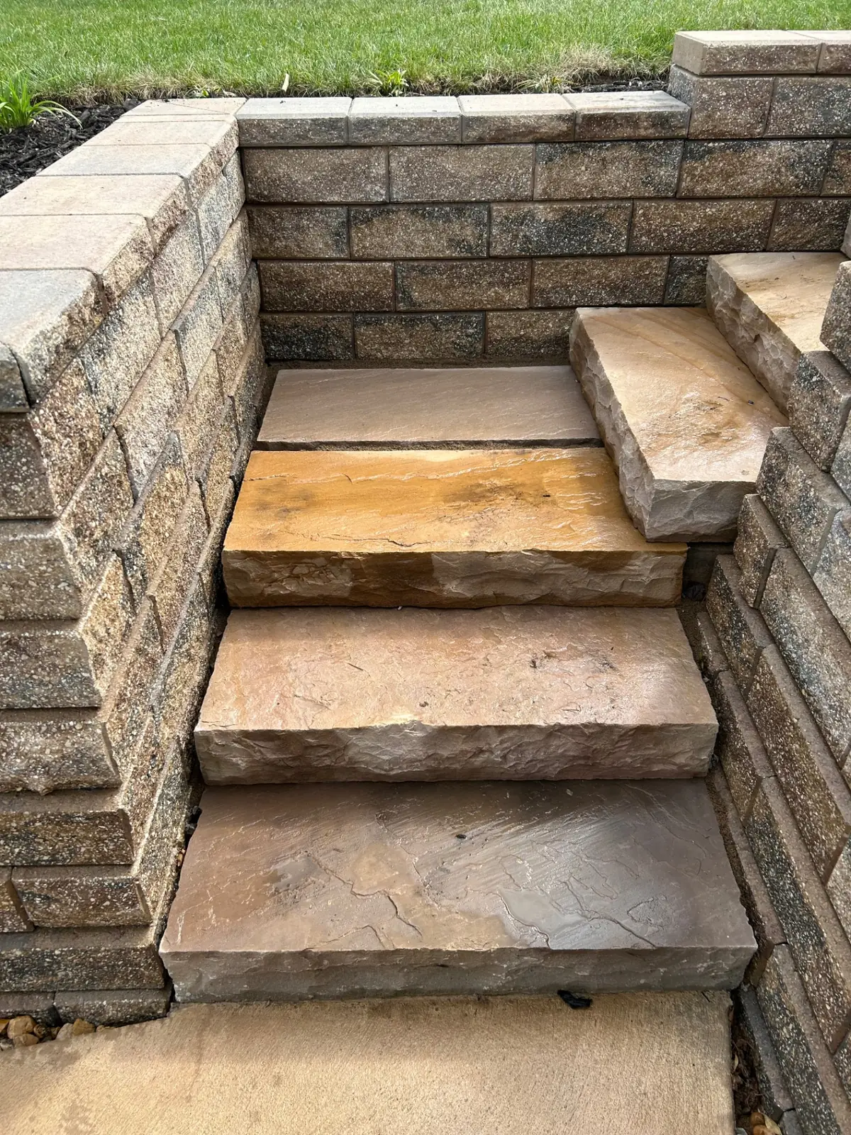 Natural sandstone slab steps precisely fitted into a textured retaining wall