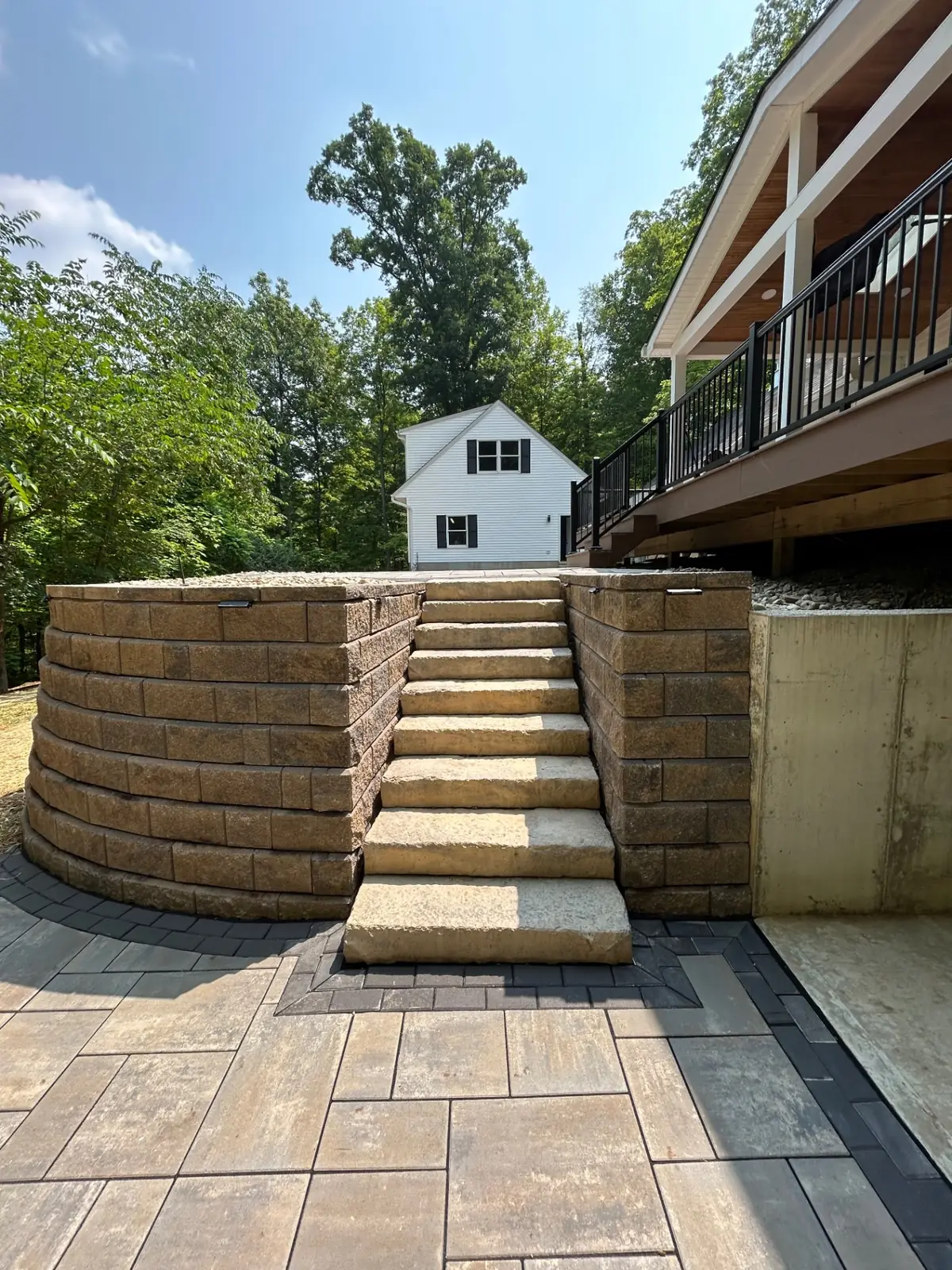 Sandstone stairs rising through a tall curved tiered retaining wall