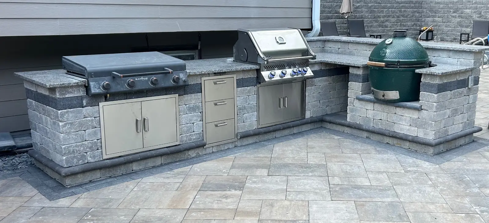 Custom masonry outdoor kitchen with stainless steel grill and stone counters
