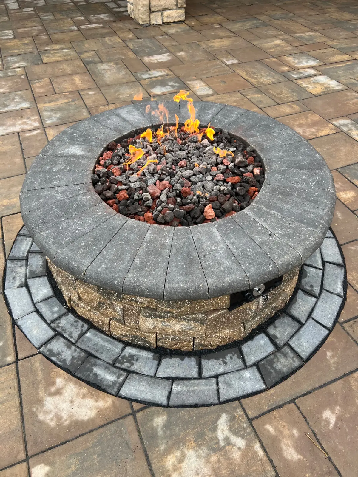 Lit gas fire pit with lava rock in a finished outdoor living space