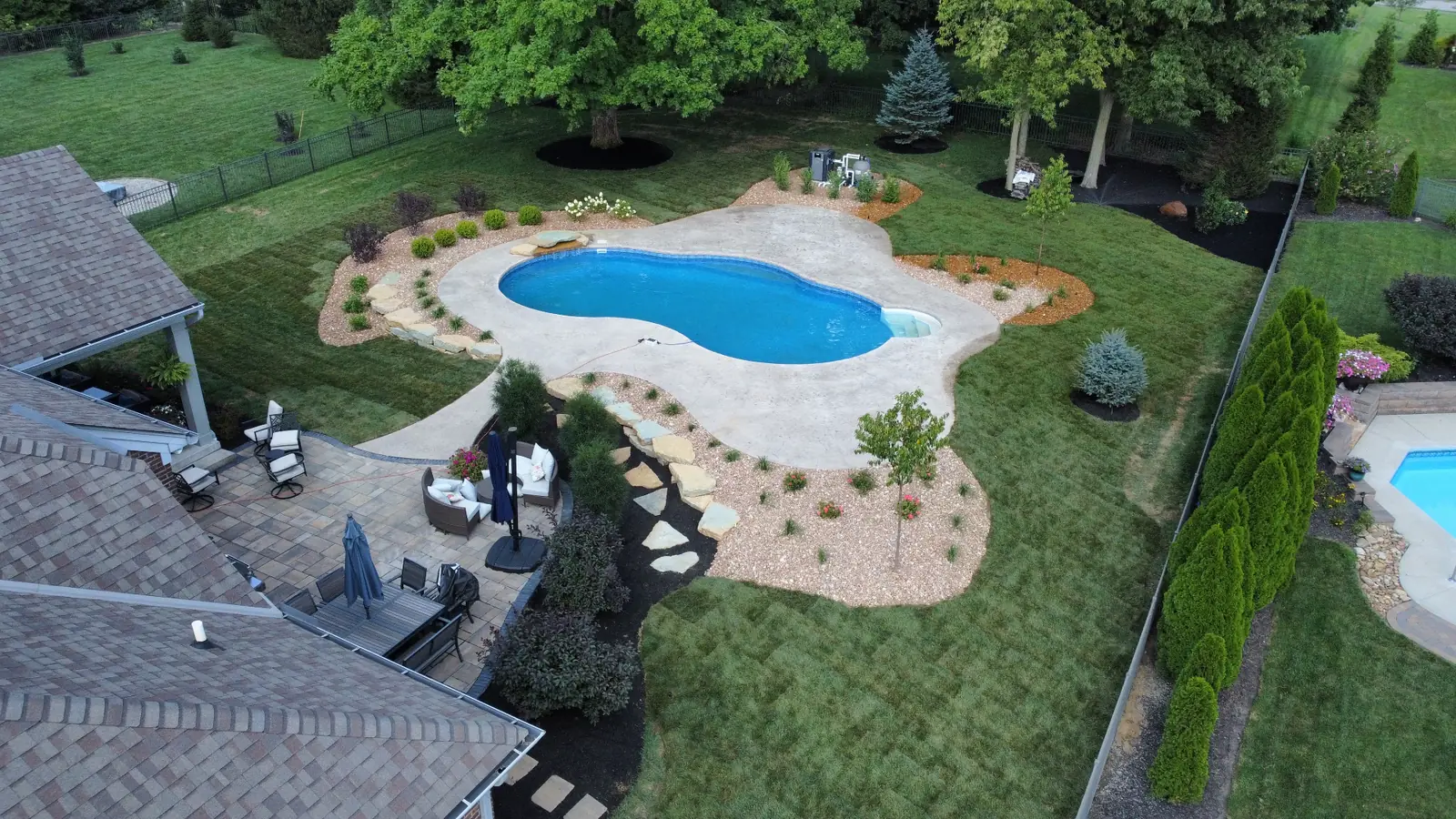 Aerial view of a freeform pool, patios and landscaped grounds completed by TJs Landscaping