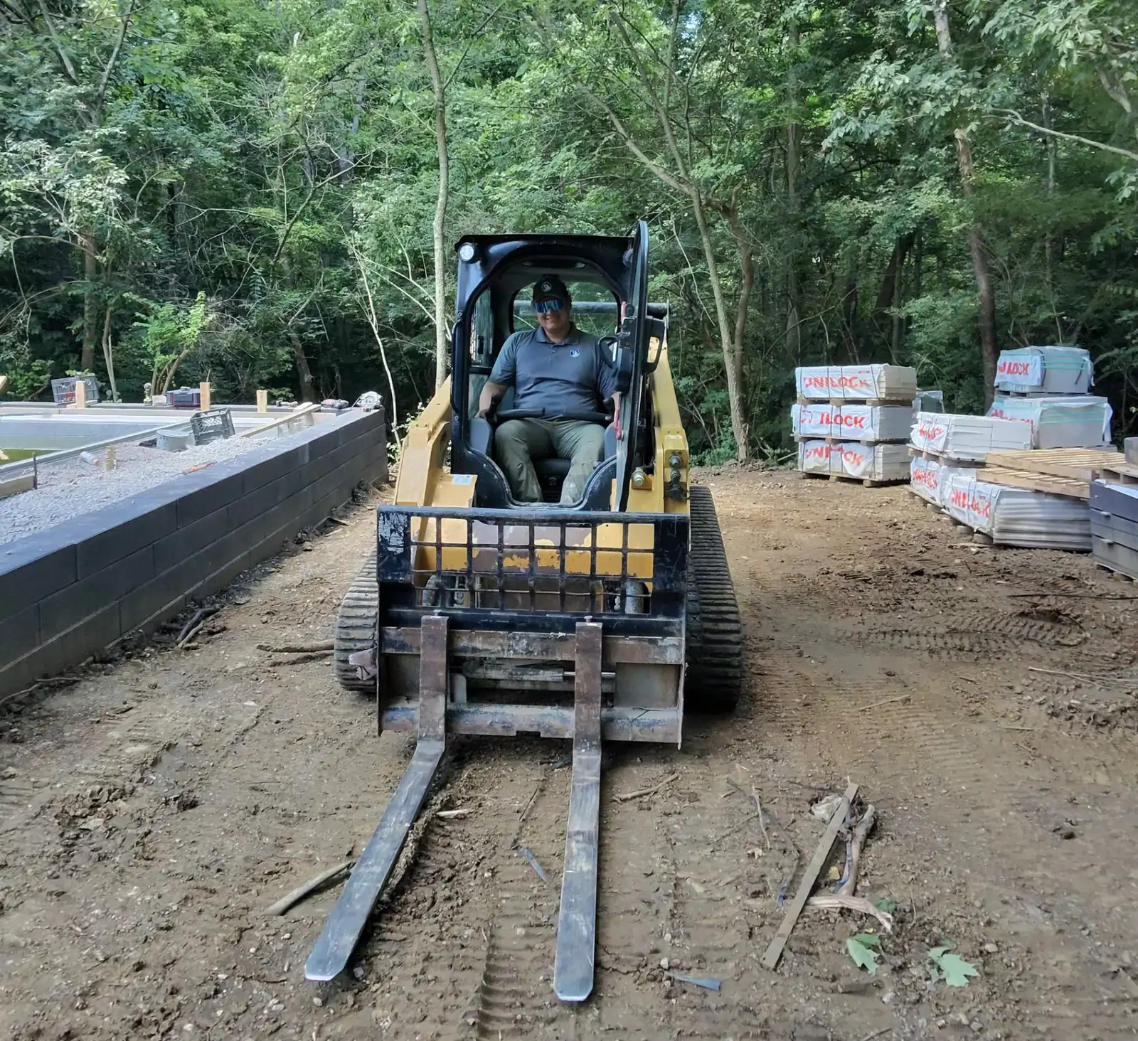 Design-Build Project Manager Alex operating a tracked loader on a TJs project site